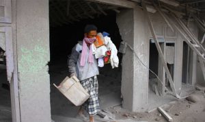 Seorang warga mengangkut barang yang bisa diselamatkan dari rumahnya yang hancur akibat erupsi gunung Semeru di desa Supiturang, Lumajang, Jawa Timur, Minggu, 5 Desember 2021. (Foto. Antara)
